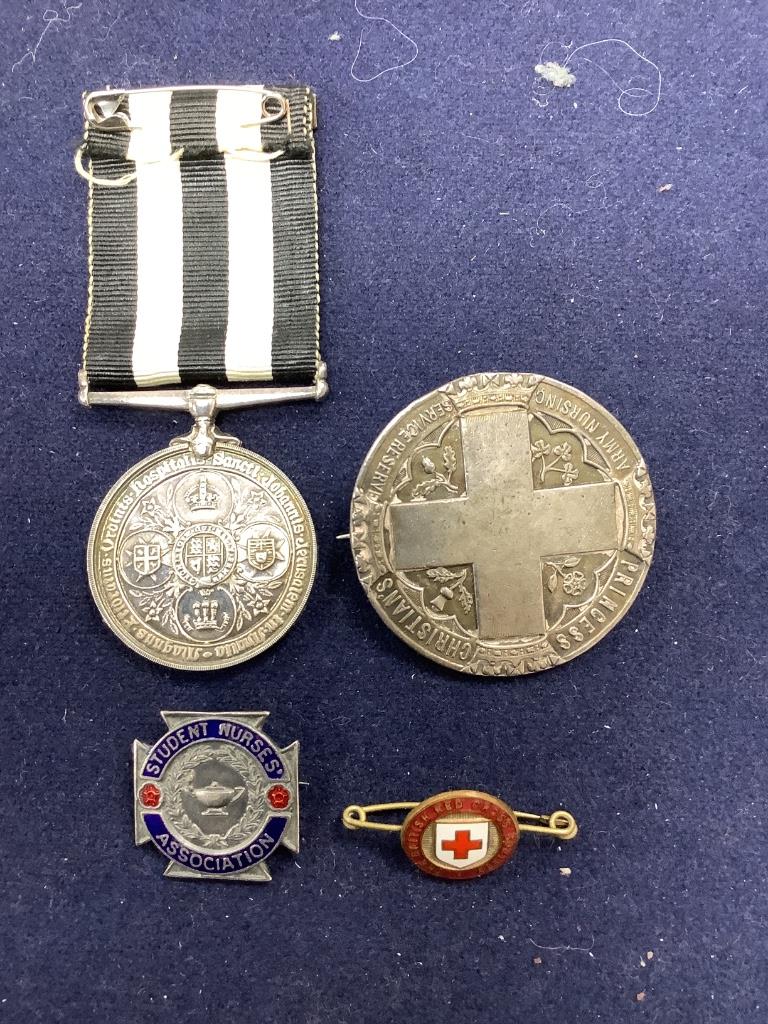 A collection of assorted enamel badges and nursing badges